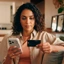 Mulher no sofá a usar o telemóvel e um cartão de crédito para um pagamento