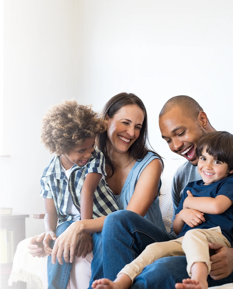  father, mother, and 2 children, sitting on the sofa, smiling