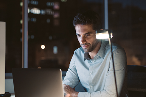 man sitting at the desk, with a laptop and a coffee cup