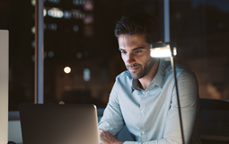 homem sentado à secretária, com portátil e chávena de café