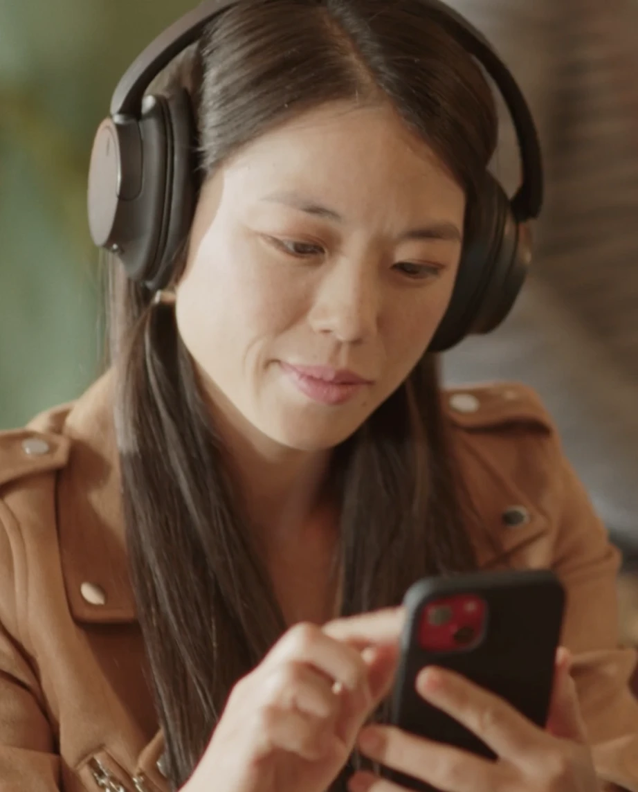 Rapariga de headphones a olhar para o seu telemóvel
