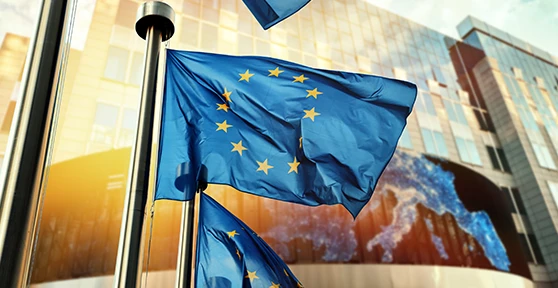 bandeira da União Europeia em frente a edifício espelhado, à luz do nascer do sol