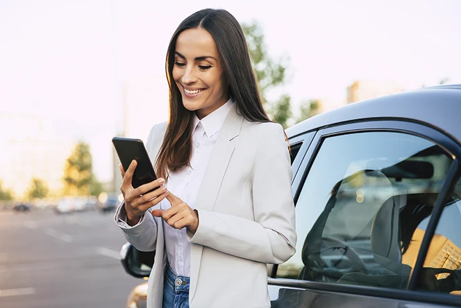 senhora com telemóvel, ao lado do seu carro