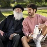 José Condessa, com caneca Stanley, e 'Darwin' (ator) sentados num banco de jardim