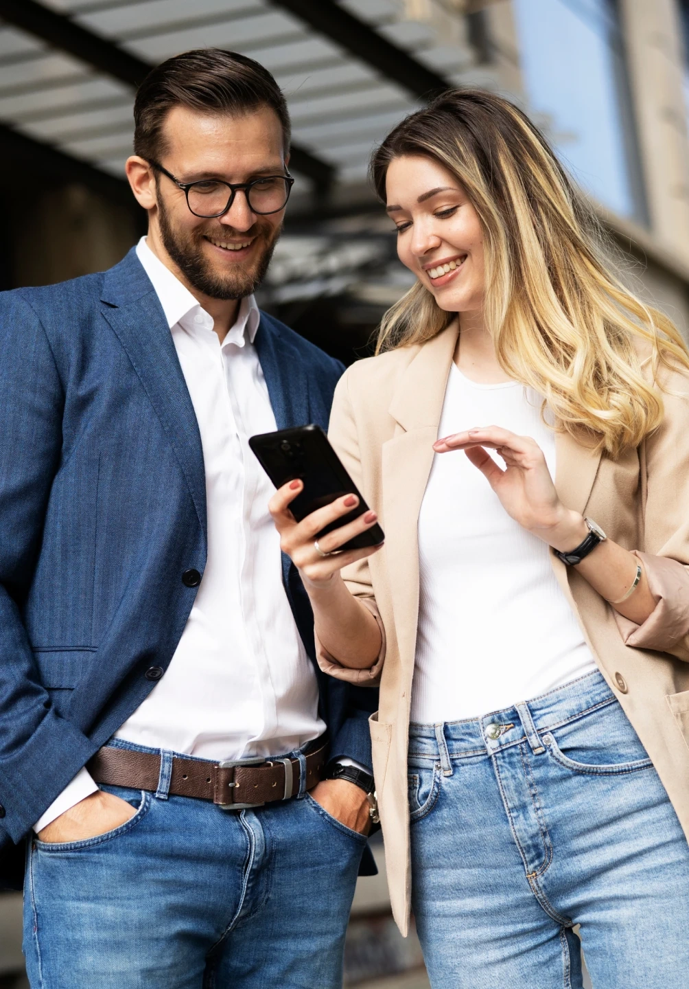 Homem e mulher sorriem enquanto olham para o ecrã de um telemóvel