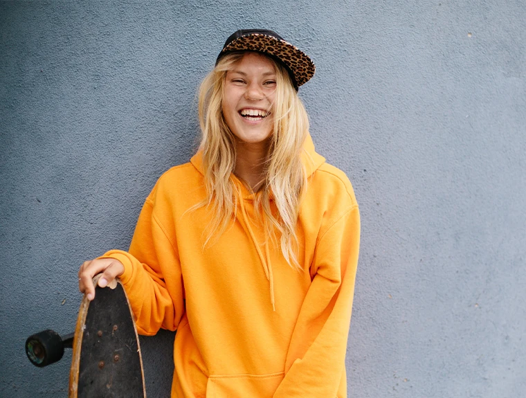 jovem sorridente com skate na mão