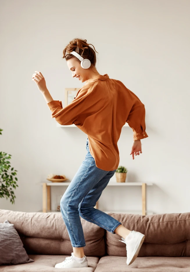 girl dancing on the sofa with headphones on