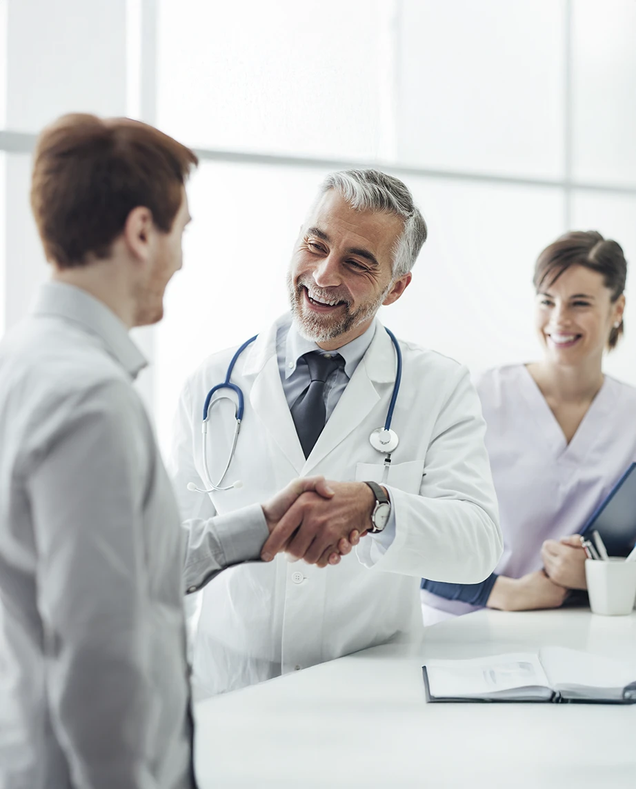 médico com estetoscópio ao pescoço, a dar aperto de mão a paciente