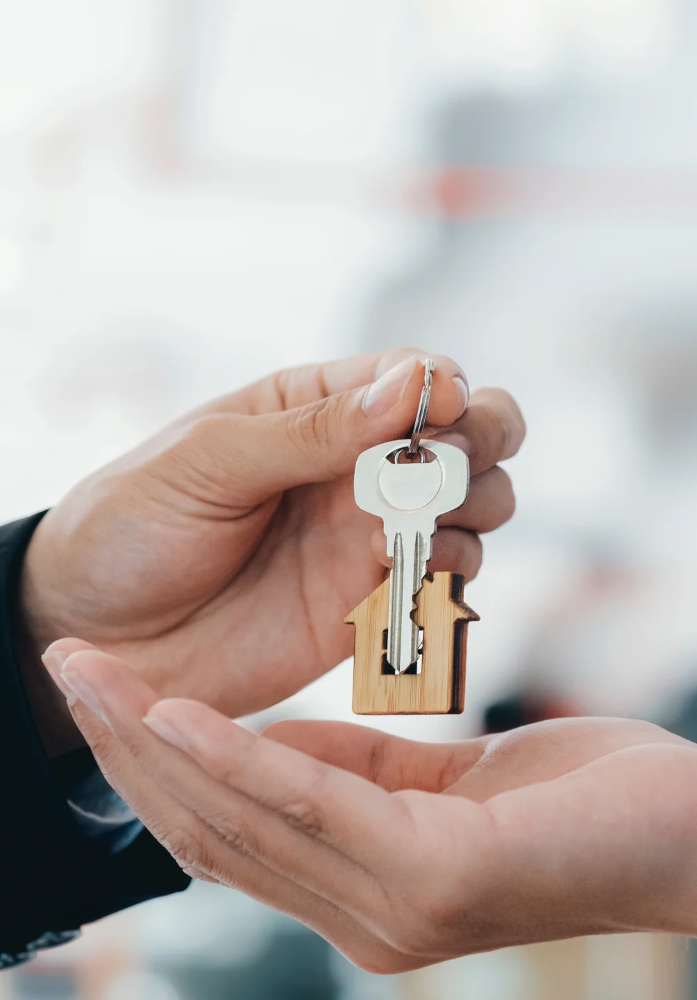 Mão a segurar chave com porta-chaves em forma de casa