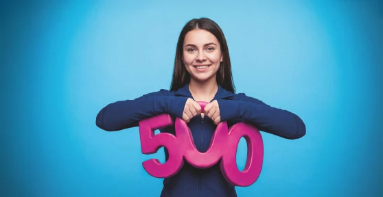 Rapariga jovem a sorrir e a pegar no numero 500