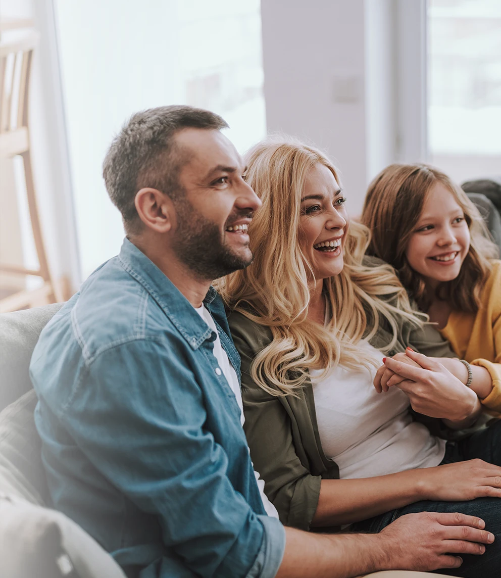 couple and young daughter in a sofa, happy, sharing cumplicity moment