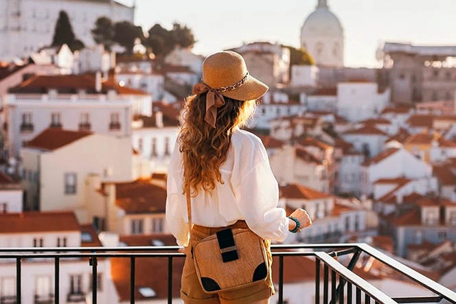 Woman with a straw hat observes a city from a viewpoint