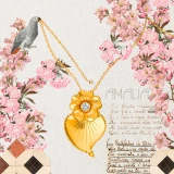 “Amália” gold necklace in an illustration where it is held by a bird, with pink flowers in the background