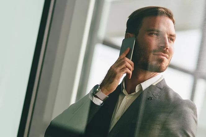 man in a suit and tie, talking on the phone, looking to the side