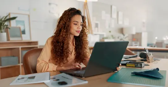 Mulher a olhar para o seu computador portátil num escritório moderno