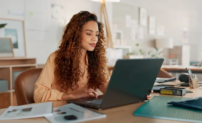 Mulher a olhar para o seu computador portátil num escritório moderno