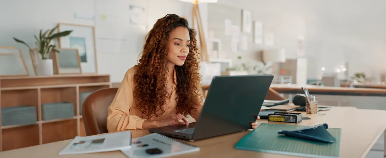 Mulher a olhar para o seu computador portátil num escritório moderno