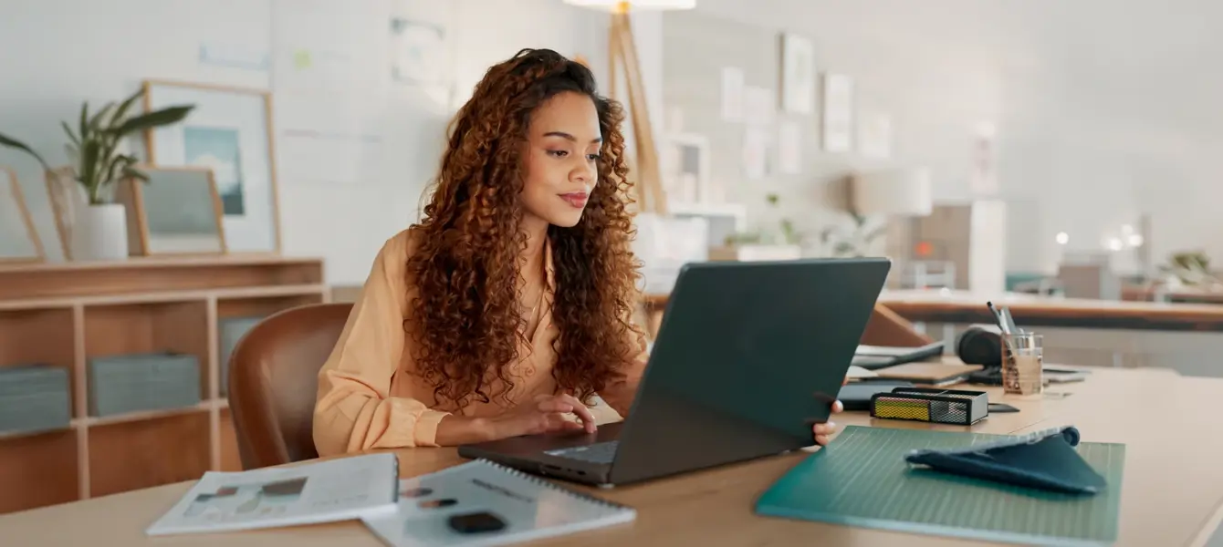 Mulher a olhar para o seu computador portátil num escritório moderno