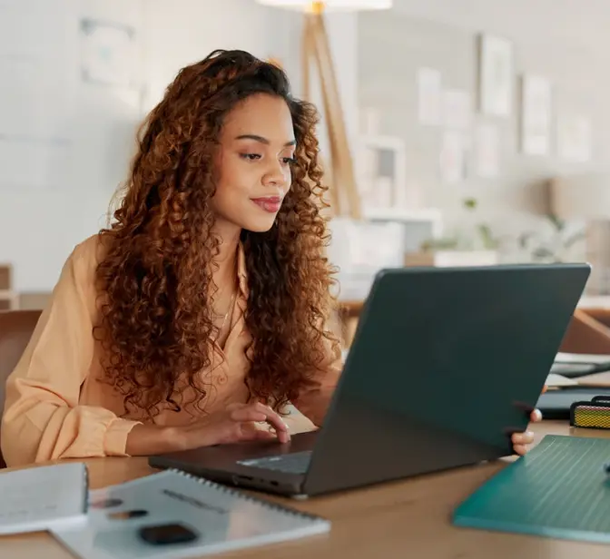 Mulher a olhar para o seu computador portátil num escritório moderno