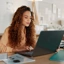 Mulher a olhar para o seu computador portátil num escritório moderno