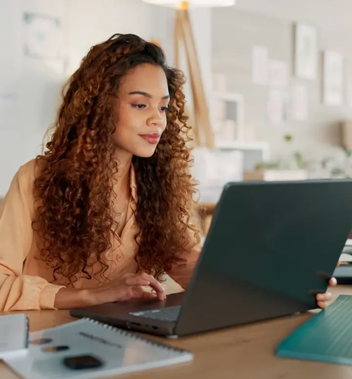 Mulher a olhar para o seu computador portátil num escritório moderno