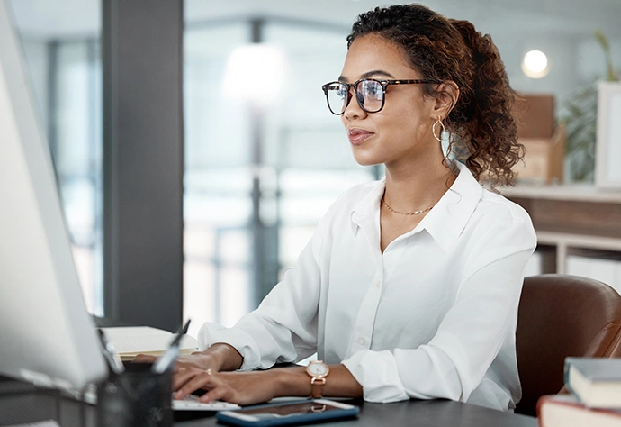 Woman with glasses working on a computer in an office environment