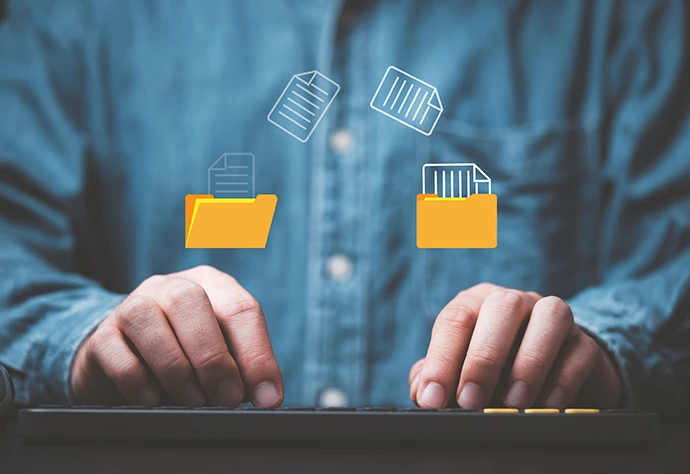 pormenor de mãos a escrever num teclado, com ilustração de icons de ficheiros