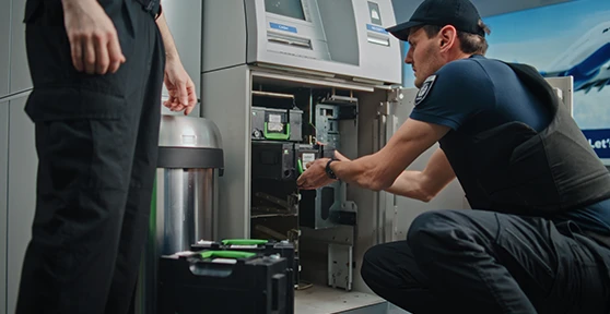 2 seguranças, um a recolher cassete de notas de uma caixa multibanco, e outro de vigia