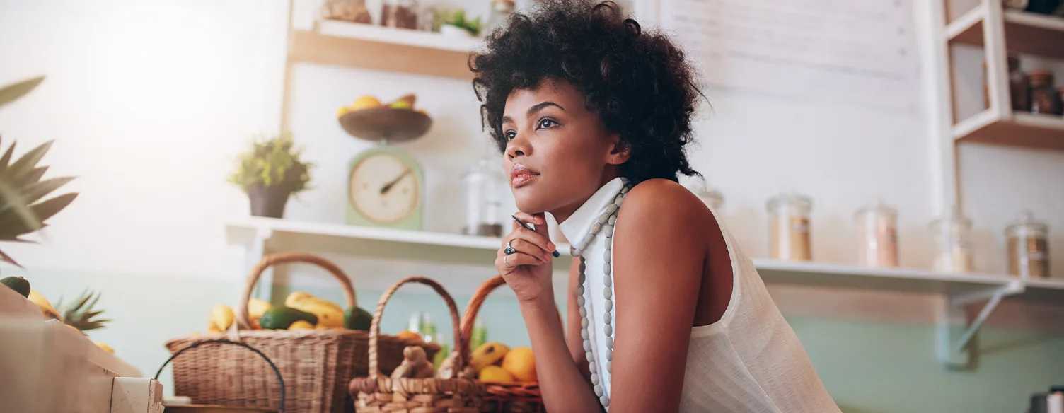 senhora com braços apoiados em mesa com cestos de fruta