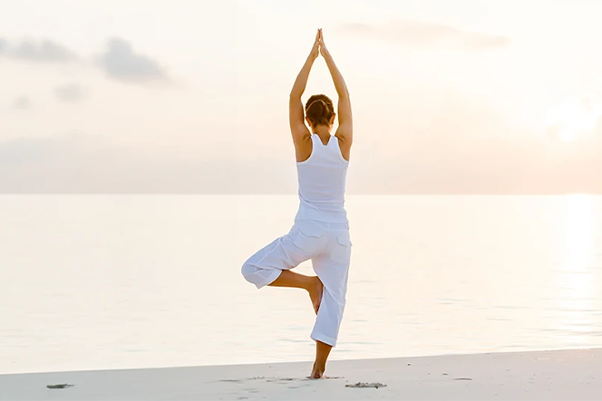 woman doing yoga on the beach at sunset