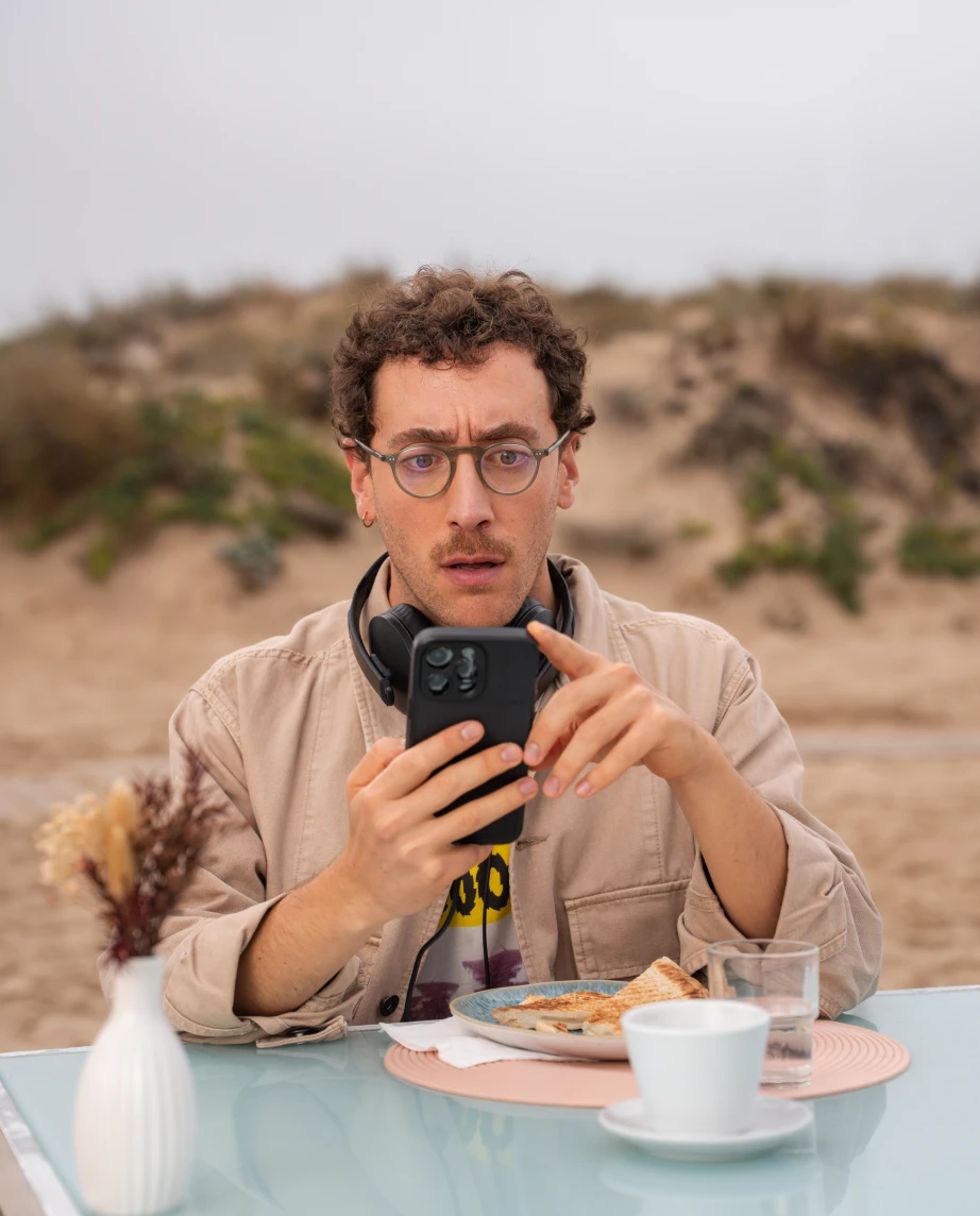 Ator, a representar a personagem Diogo Pinto, a olhar para o seu telemóvel com um ar surpreendido