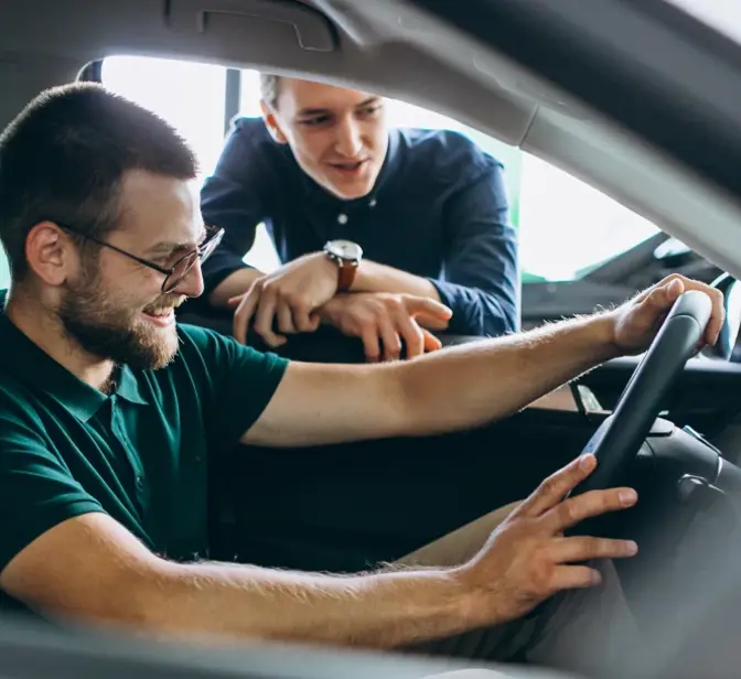 Homem a testar carro novo com vendedor a dar explicações