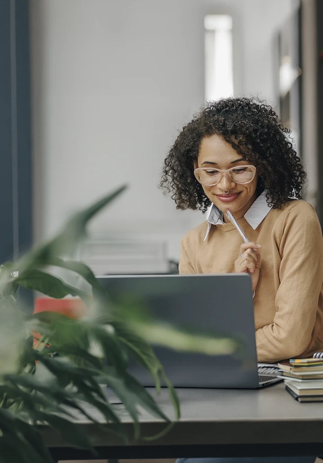 Woman smiles while working on her laptop at a desk