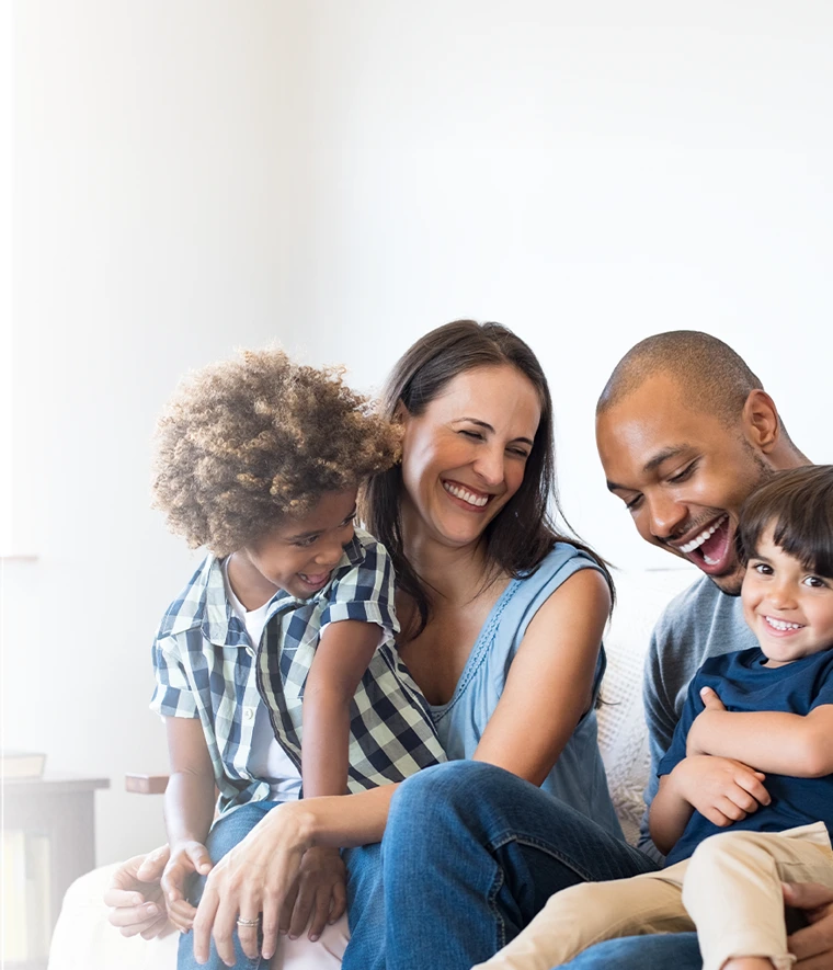  father, mother, and 2 children, sitting on the sofa, smiling