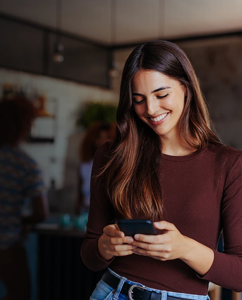 woman smilling while looking at her phone