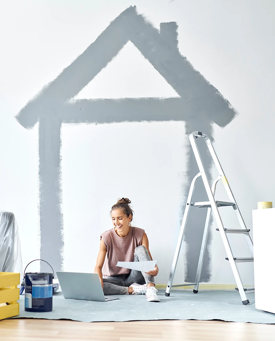 woman sitting on the floor in a house under renovation, with a laptop