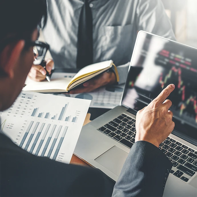 Pessoa com graficos em papel e com o computador aberto a comparar