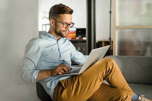 homem sentado num sofá, com computador