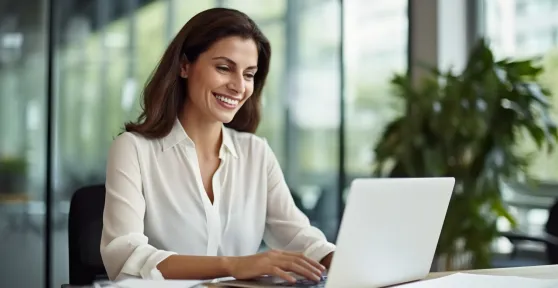 Mulher de camisa branca a olhar para o seu computador portátil