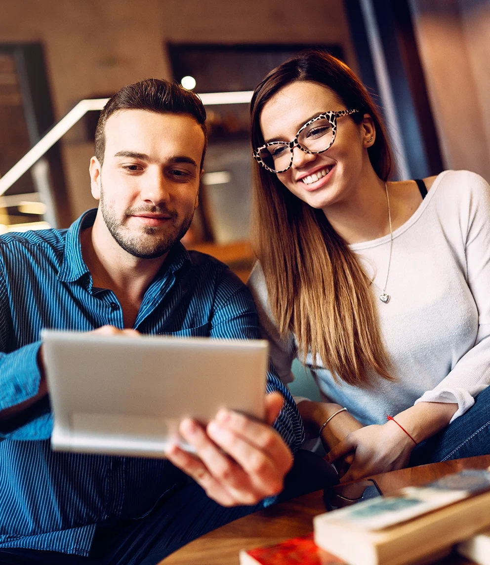 couple sitting on coffee table, holding tablet