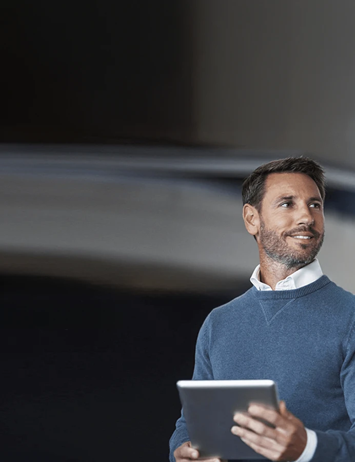 homem com camisola azul e tablet na mão