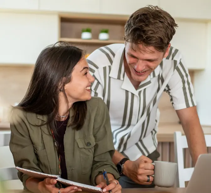 Casal jovem conversa sobre o orçamento familiar na cozinha, usando um computador portátil