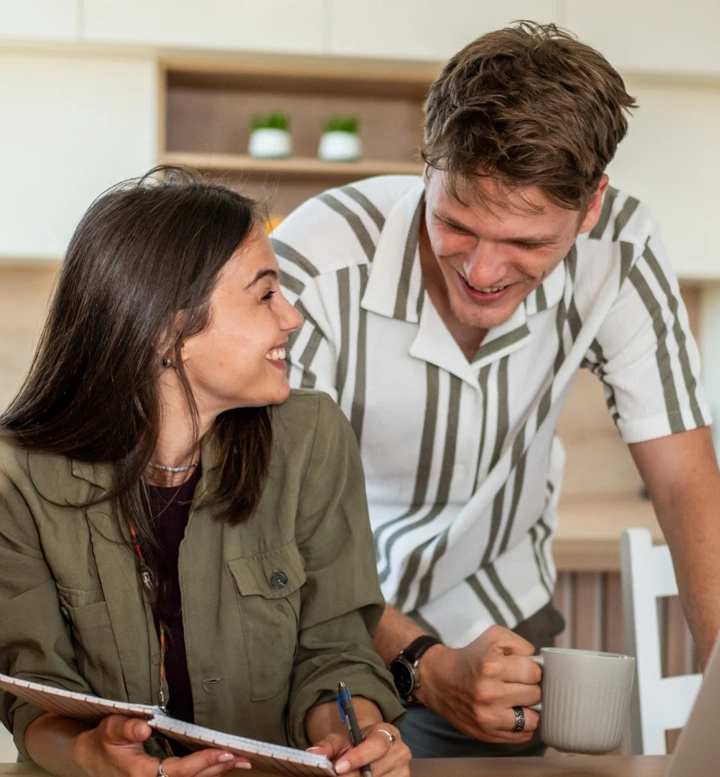 Casal jovem conversa sobre o orçamento familiar na cozinha, usando um computador portátil