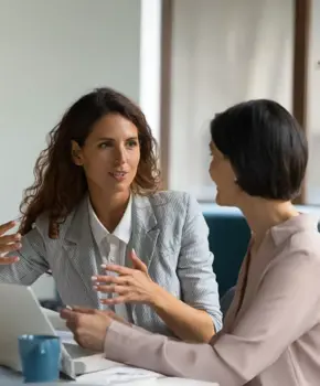 Duas empresárias a discutir trabalho numa mesa com um portátil
