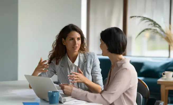 Duas empresárias a discutir trabalho numa mesa com um portátil