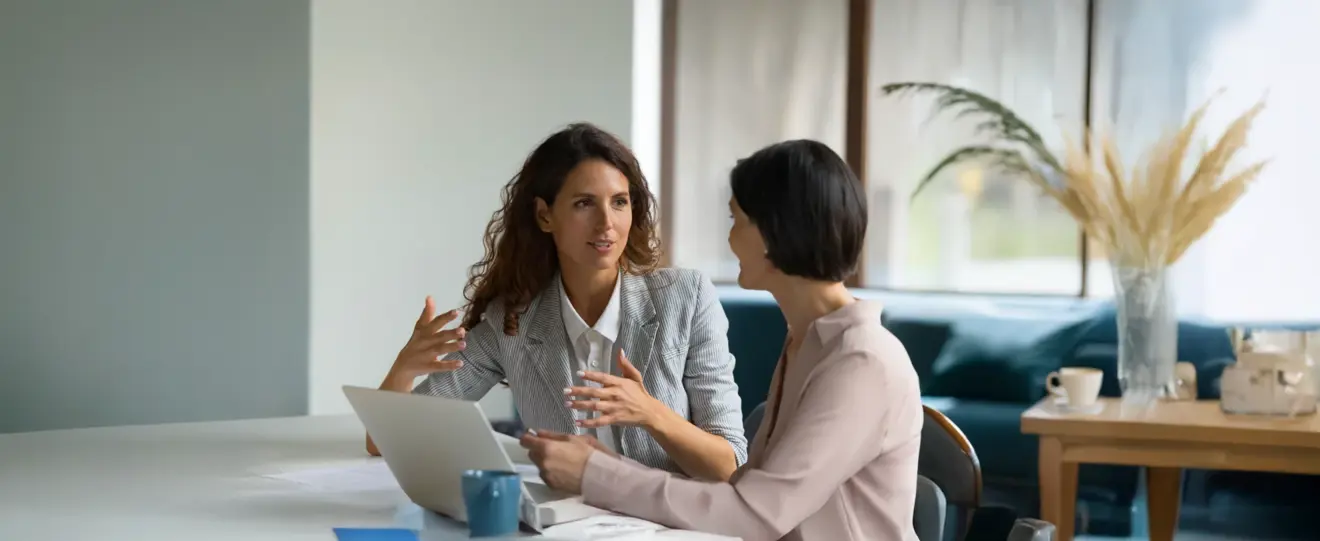 Duas empresárias a discutir trabalho numa mesa com um portátil