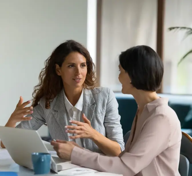 Duas empresárias a discutir trabalho numa mesa com um portátil