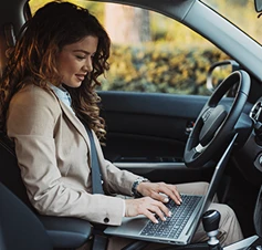 senhora sentada no carro, com computador ao colo