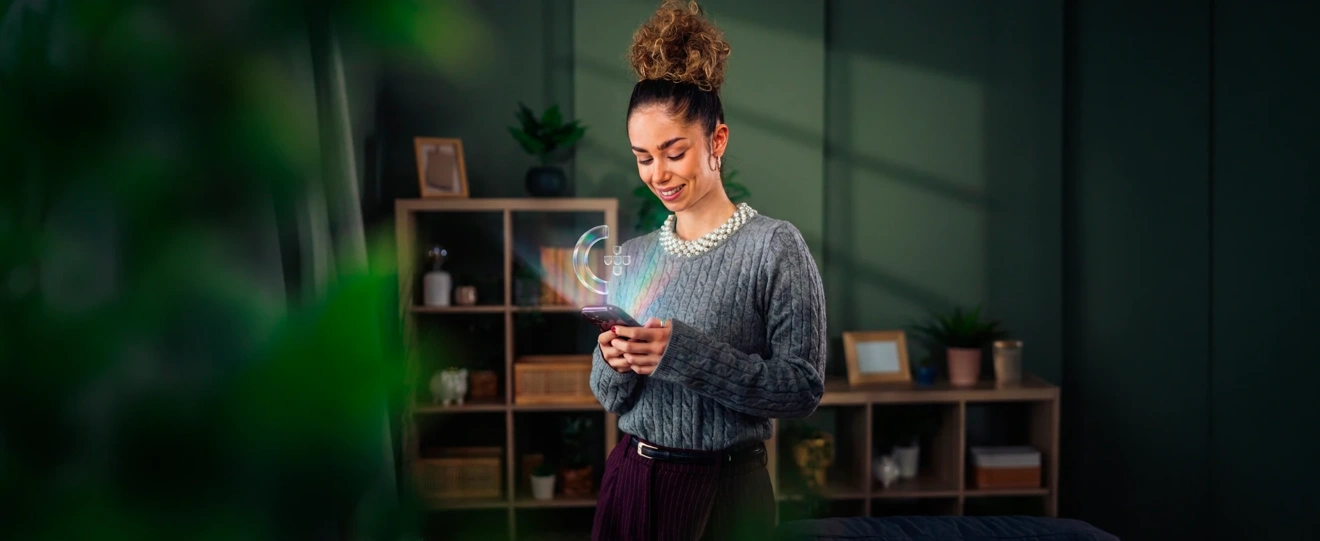 Mulher com telemóvel de onde sai o ícone da Chave Móvel Digital