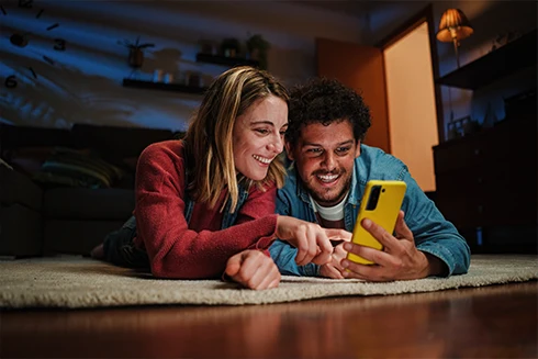  young couple lying on the floor, using their phones